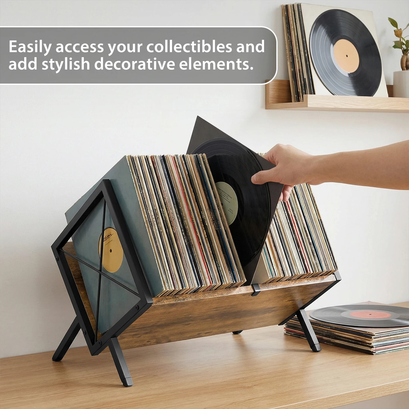 Une main sort un vinyle du support posé sur un meuble, les pochettes voisines restent en place