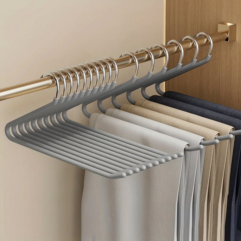 Le lot de dix cintres en Z gris alignés sur une tringle de penderie, pantalons beiges et bleu marine suspendus
