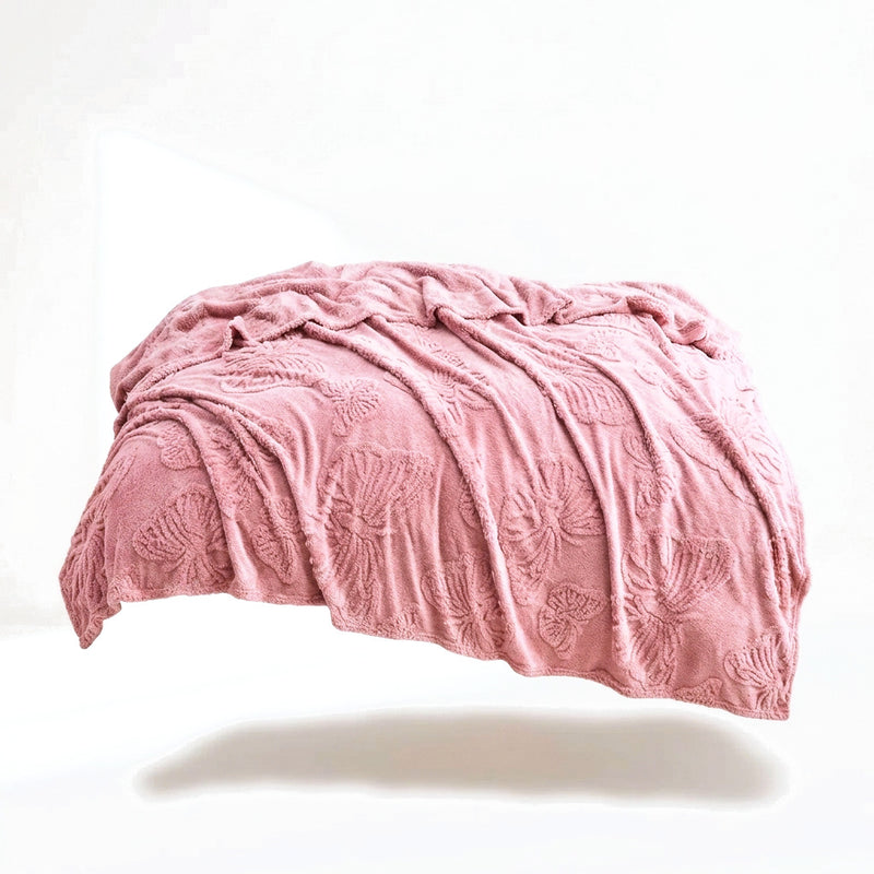 Le plaid rose poudré drapé sur fond blanc, motif de papillons tissé en relief