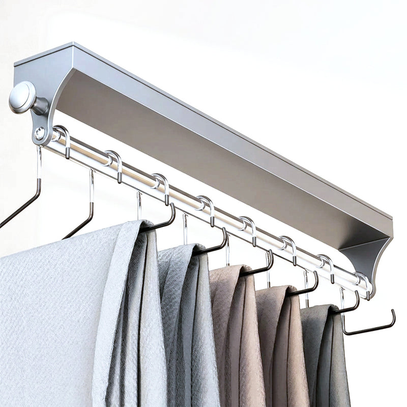 Tringle coulissante grise sortie de son caisson, une rangée de pantalons suspendus aux cintres